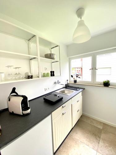 une cuisine avec des placards blancs et un comptoir noir dans l'établissement Apartment-Casa Seestern, à Langenargen