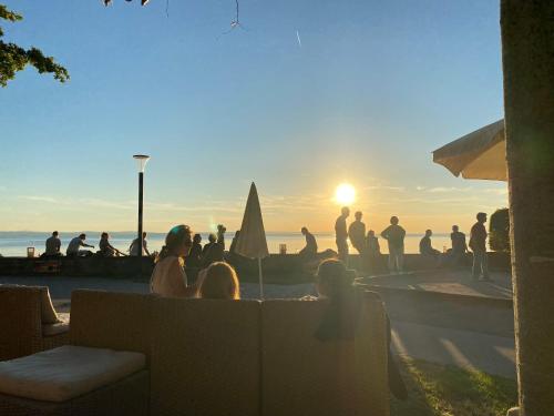 - un groupe de personnes assis autour d'une piscine pour admirer le coucher du soleil dans l'établissement Apartment-Casa Seestern, à Langenargen