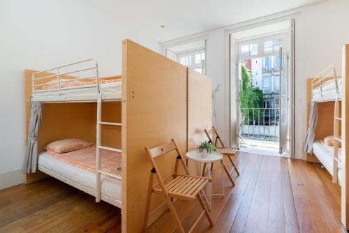 a room with bunk beds and a table and a chair at Porto Lounge Hostel & Guesthouse in Porto