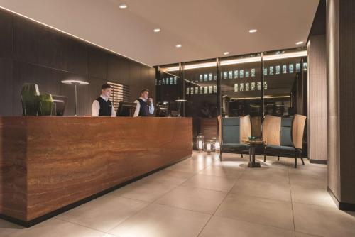 two men standing at a bar in a restaurant at Adina Apartment Hotel Hamburg Speicherstadt in Hamburg