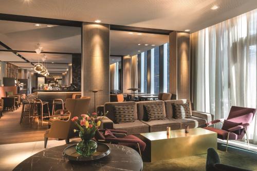 a hotel lobby with a couch and tables and chairs at Adina Apartment Hotel Hamburg Speicherstadt in Hamburg