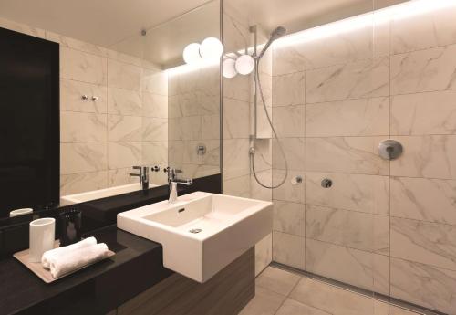 a bathroom with a white sink and a shower at Adina Apartment Hotel Hamburg Speicherstadt in Hamburg