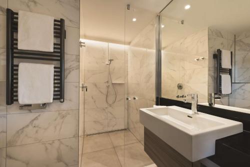 a white bathroom with a sink and a shower at Adina Apartment Hotel Hamburg Speicherstadt in Hamburg
