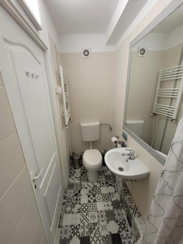 a white bathroom with a toilet and a sink at Capra Vecinului in Târgu-Mureş