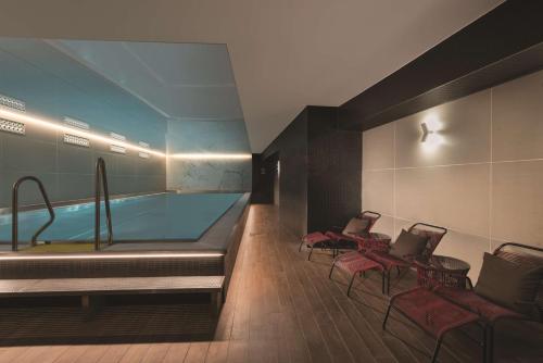 a room with a pool with chairs and a table at Adina Apartment Hotel Nuremberg in Nuremberg