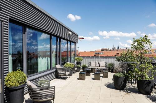 een patio met stoelen en planten op een gebouw bij Adina Apartment Hotel Nuremberg in Neurenberg