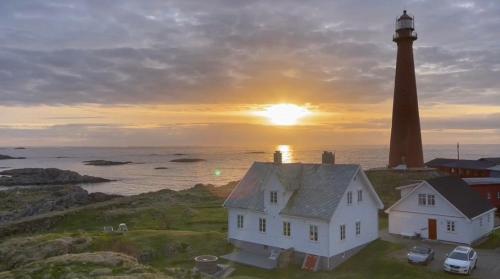 a lighthouse with a house in front of the ocean at Den gamle Fyrmesterboligen in Andenes