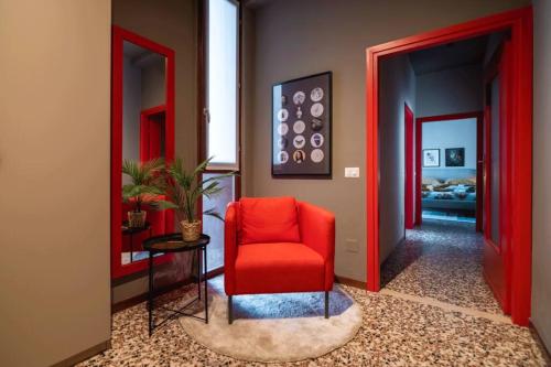 a red chair in a hallway with a bedroom at Convivium in Melegnano