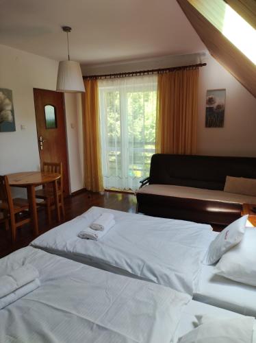 a bedroom with two beds and a couch and a table at Rezydencja Bukowy Dwór in Czarna