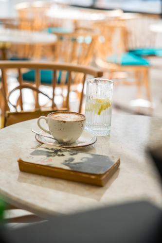 a cup of coffee on a table next to a glass at Niss Lara Hotel in Antalya