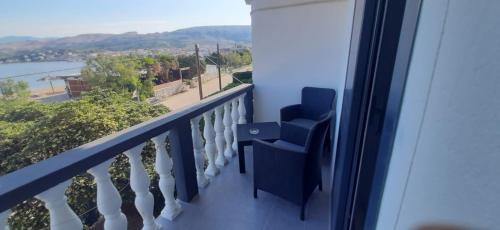 balcón con sillas azules y vistas al agua en Rooms & Apartments Kaurloto, en Pag