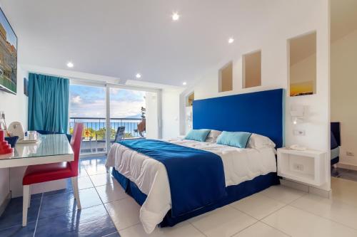 una camera da letto blu e bianca con letto e scrivania di Hotel Metropole a Sorrento