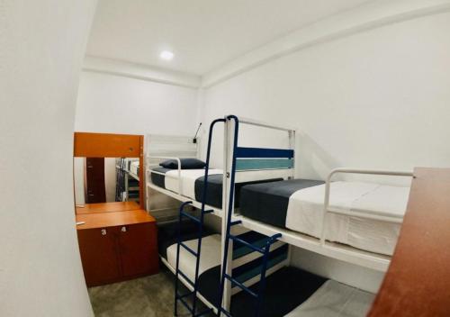 Hangover Hostels Arugam Bay في آروغام باي: غرفة صغيرة مع سريرين بطابقين ومكتب