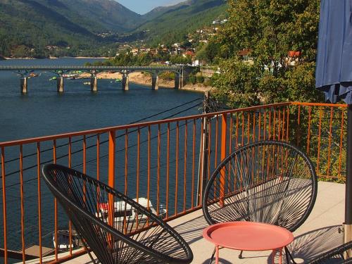 two chairs and a table on a balcony overlooking a river at Ancoradouro T2 - Alojamento Local Gerês in Braga