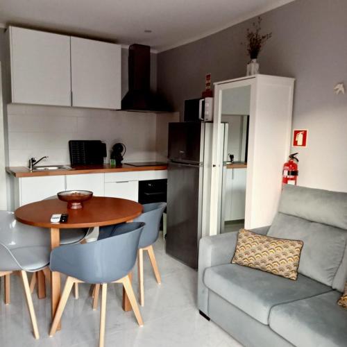a living room with a table and a couch and a kitchen at Ancoradouro T2 - Alojamento Local Gerês in Braga