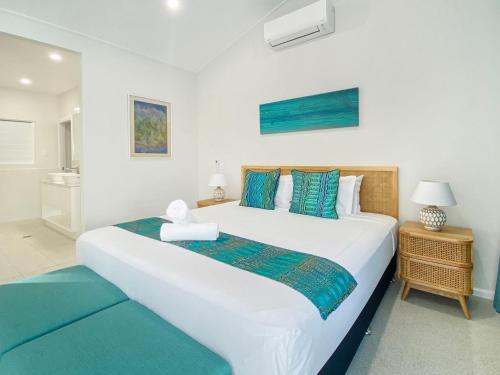 1 dormitorio con 1 cama blanca grande con almohadas azules en Rock Salt Villa 1, en Picnic Bay