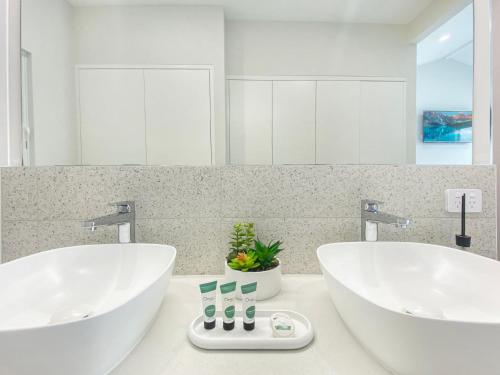 2 lavabos blancos en un baño con espejo en Rock Salt Villa 1 en Picnic Bay