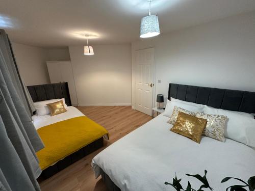 a bedroom with two beds and a yellow blanket at Trinity's Place in Wythenshawe