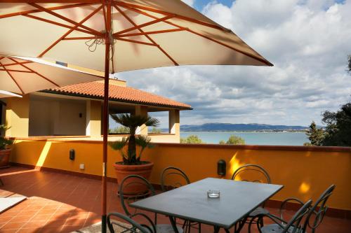 a patio with a table and chairs and an umbrella at Albergo Filippo II in Porto Santo Stefano