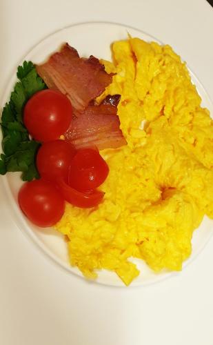 a plate of scrambled eggs and bacon and tomatoes at Arbia Dorka Heritage Palace in Varaždin