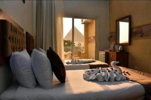1 dormitorio con 2 camas con cisnes y una ventana en king ramses pyramids view apartment en El Cairo