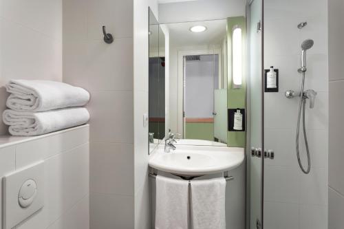 La salle de bains blanche est pourvue d'un lavabo et d'une douche. dans l'établissement B&B HOTEL Zaragoza Plaza Mozart, à Saragosse