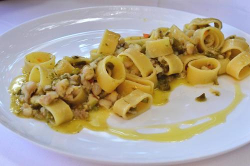 a white plate of pasta with shrimp and sauce at Albergo Filippo II in Porto Santo Stefano