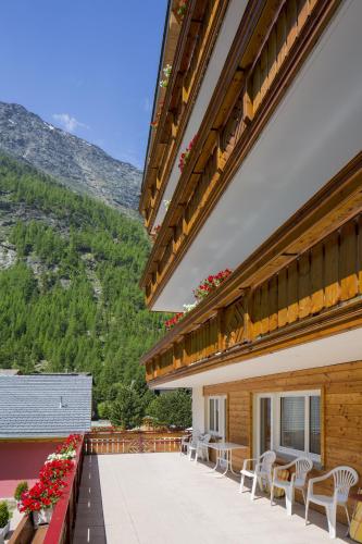 a balcony of a building with chairs and flowers at Wellness- und Schneesporthotel Christiania in Saas-Almagell