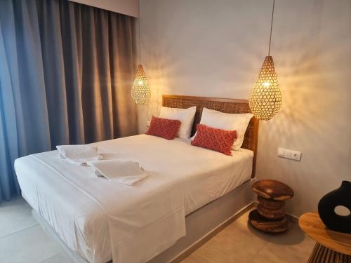 a bedroom with a bed with white sheets and red pillows at Artemis in Makry Gialos