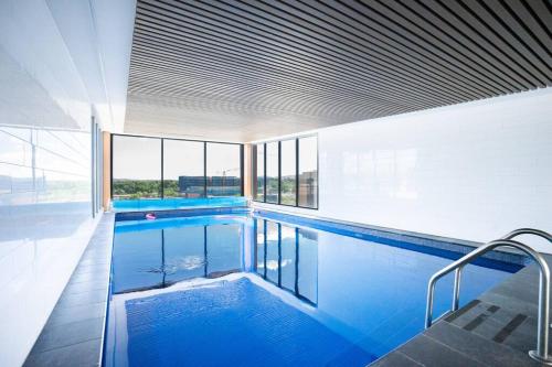 a large swimming pool with blue water in a building at Lux 2 Bed 2 Bath Secure Parking Apartment in the Heart of Dickson, Canberra in Canberra