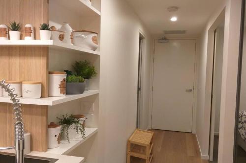 a hallway with shelves with potted plants and a door at Lux 2 Bed 2 Bath Apartment in the Heart of Dickson, Canberra in Canberra