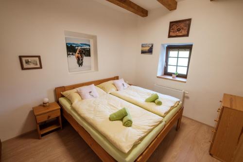 1 dormitorio con 1 cama con sábanas blancas y almohadas verdes en Penzion U Fořta, en Rožmberk nad Vltavou