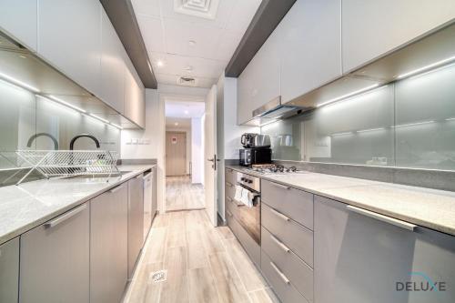 a large kitchen with stainless steel appliances and wood floors at Placid 2BR with Assistant Room at Mesk 1 Midtown Dubai Production City by Deluxe Holiday Homes in Dubai
