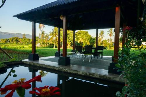 a pavilion with a table and chairs next to a pond at Gubuk Kurnia in Sawan