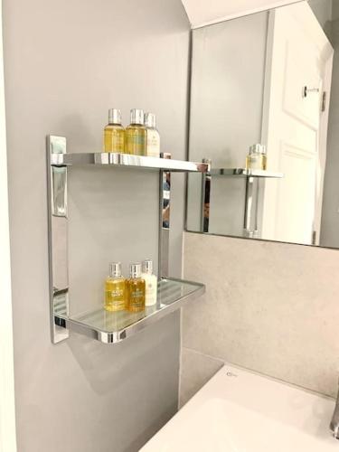 a bathroom with three shelves with jars of honey at Scholar's Loft - Cosy & Close to Central Cambridge in Cambridge