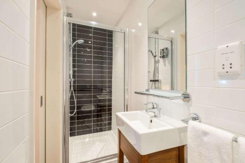 a white bathroom with a sink and a shower at KC Inn Hotel in London