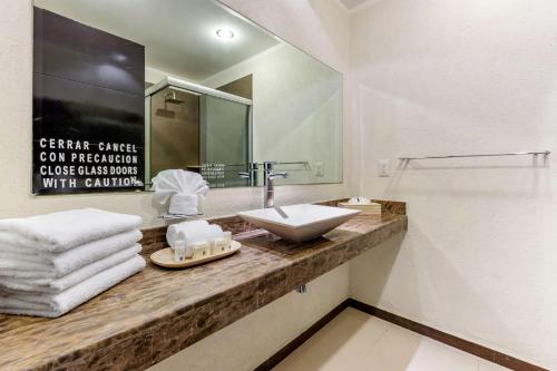 a bathroom with a sink and a mirror and towels at Comfort Inn Cancún Aeropuerto in Cancún
