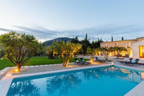 a swimming pool with chairs and a house at Can Tortet in Pollença