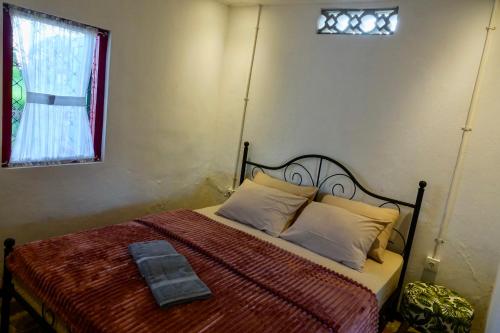 um quarto com uma cama com um cobertor vermelho e uma janela em Gubuk Kurnia em Sawan