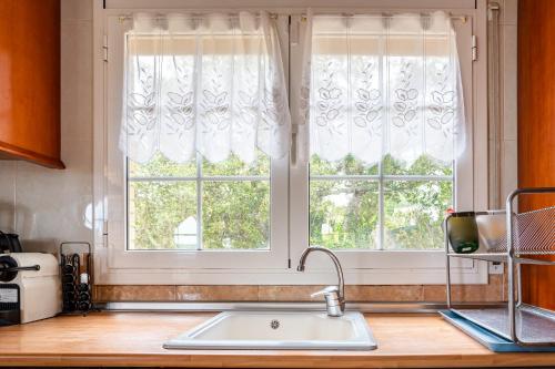 a kitchen counter with a sink and two windows at Villa Yulia in Vidreres