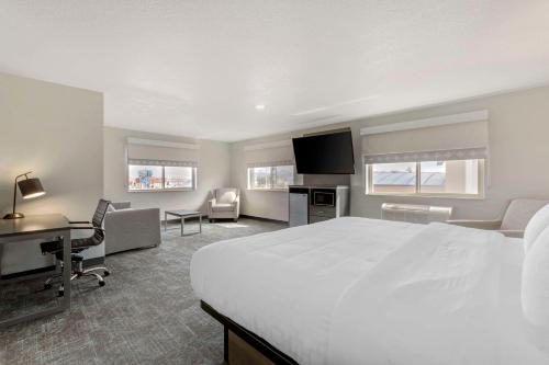 Habitación de hotel con cama blanca grande y escritorio. en Clarion Pointe Prescott Valley, en Prescott Valley