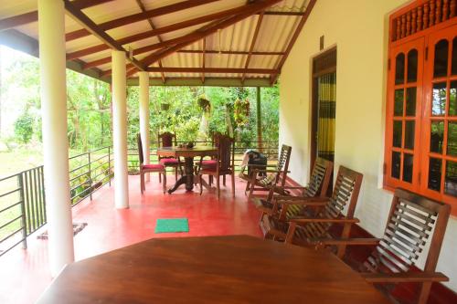 a porch with a wooden table and chairs at Canal Side Safari Resort in Udawalawe