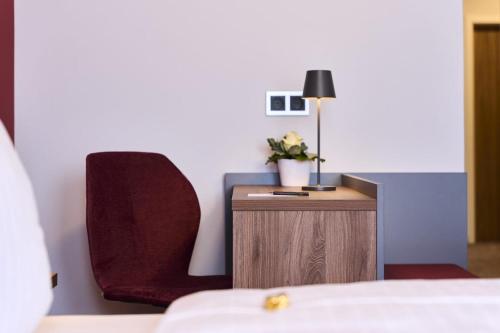 a bedroom with a bed and a chair and a table at Hotel Rhönkitz in Bad Kissingen