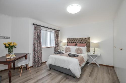 a bedroom with a bed and a desk and a window at Wees Gerus in Yzerfontein