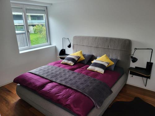a bedroom with a large bed with purple sheets and pillows at Les Cubes in Martigny-Ville