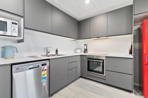 una cocina con electrodomésticos de acero inoxidable y armarios grises en Moreton Views!, en Beachmere