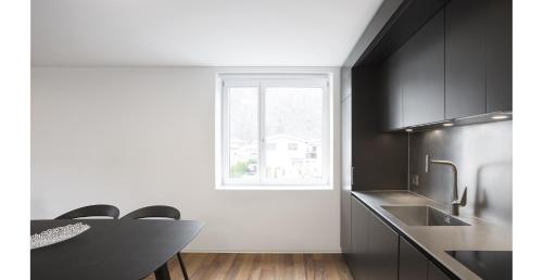 a kitchen with black cabinets and a table and a window at Les Cubes in Martigny-Ville