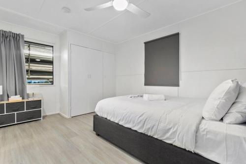 ein weißes Schlafzimmer mit einem Bett und einem Deckenventilator in der Unterkunft Moreton Views! in Beachmere