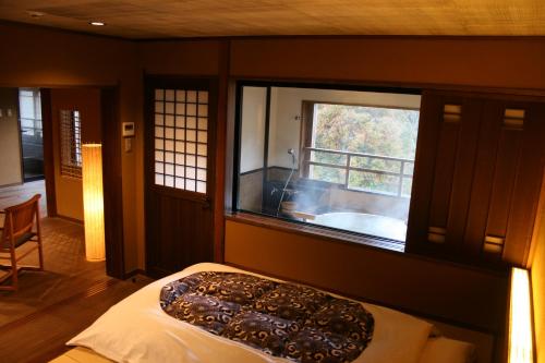 a bedroom with a large window and a bath tub at Ryokan Sumiya Kihoan in Kameoka