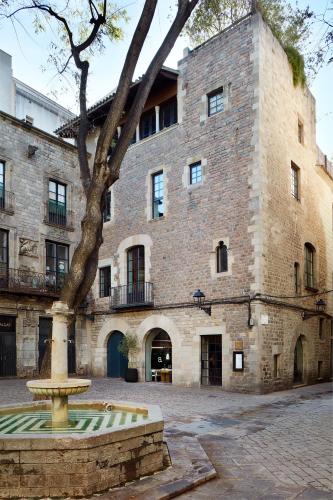 a large brick building with a fountain in front of it at Hotel Neri – Relais & Chateaux in Barcelona